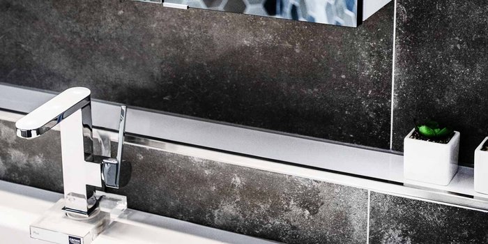 Der Wasserhahn mit klaren Linien und einer minimalistischen Form reflektiert das Licht in einem modernen Badezimmerambiente.