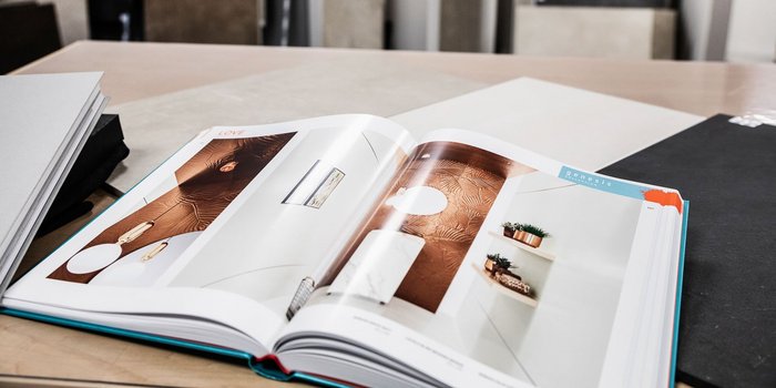 Ein Designbuch liegt auf einem Tisch und zeigt inspirierende Raumgestaltungen mit Pflanzen und dekorativen Elementen.