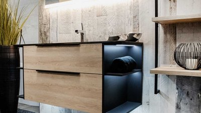 Der Raum zeigt eine harmonische Kombination aus Holz und Schwarz, ergänzt durch Pflanzen und stilvolle Badezimmeraccessoires.